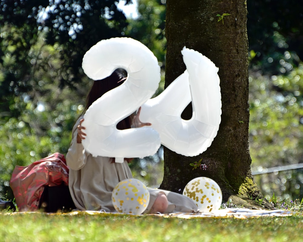 a woman laying on the ground with a large number balloon