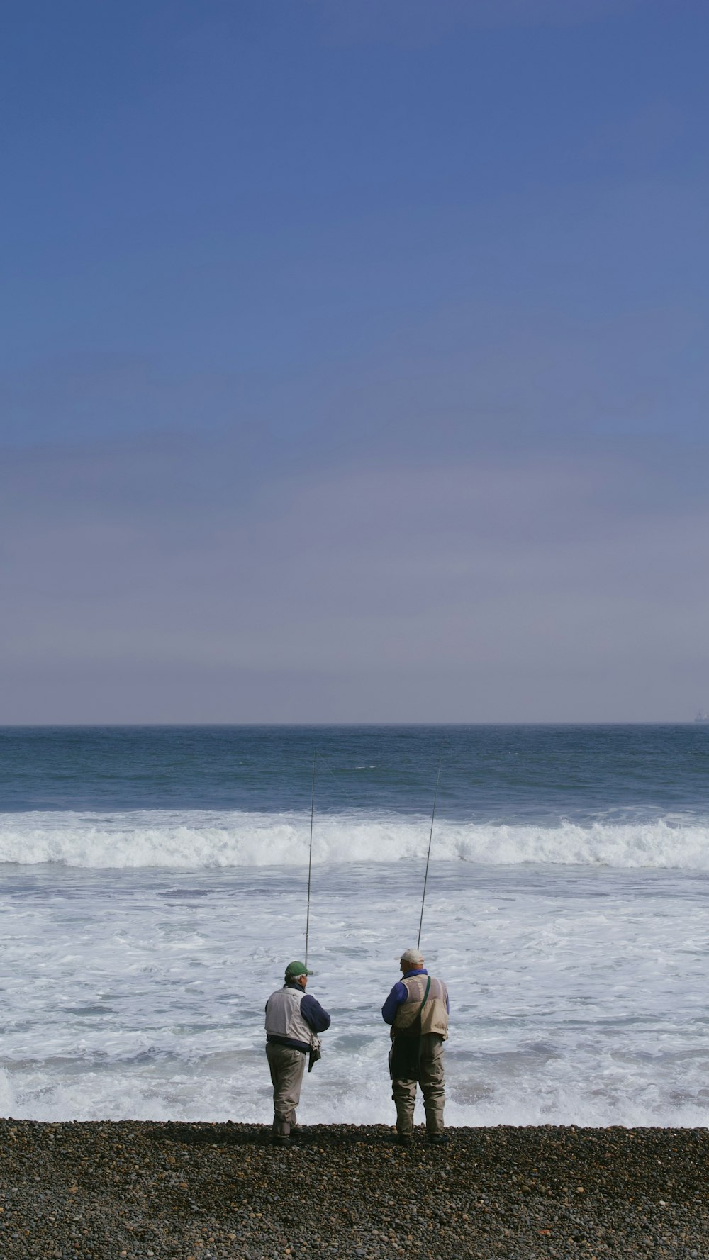 a couple of men standing on top of a beach next to the ocean