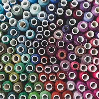 a pile of spools of different colors of thread