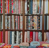 A colorful array of lawn fabric rolls arranged neatly, highlighting the variety in prints and embroidery styles.