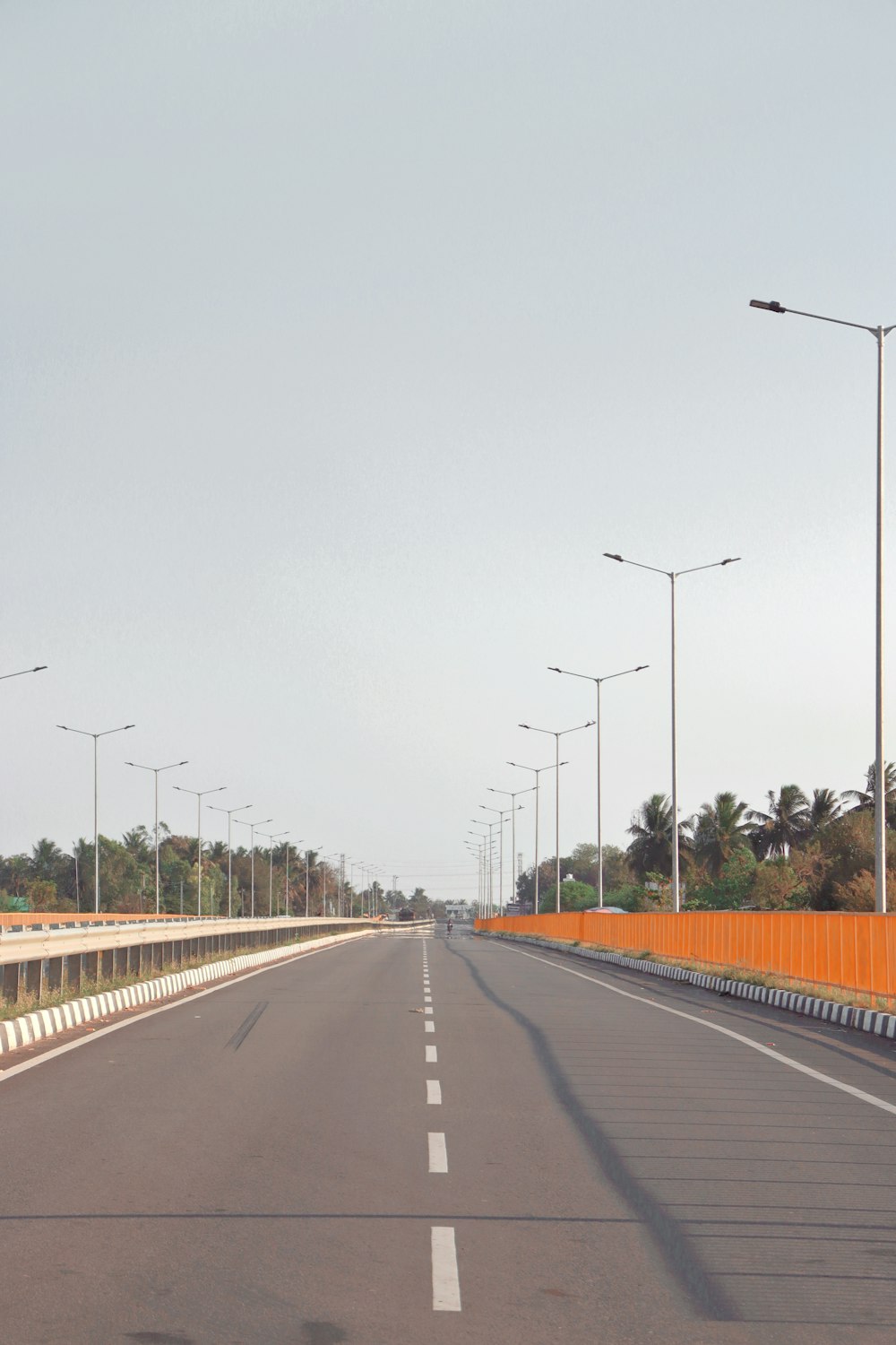 an empty highway with street lights on either side