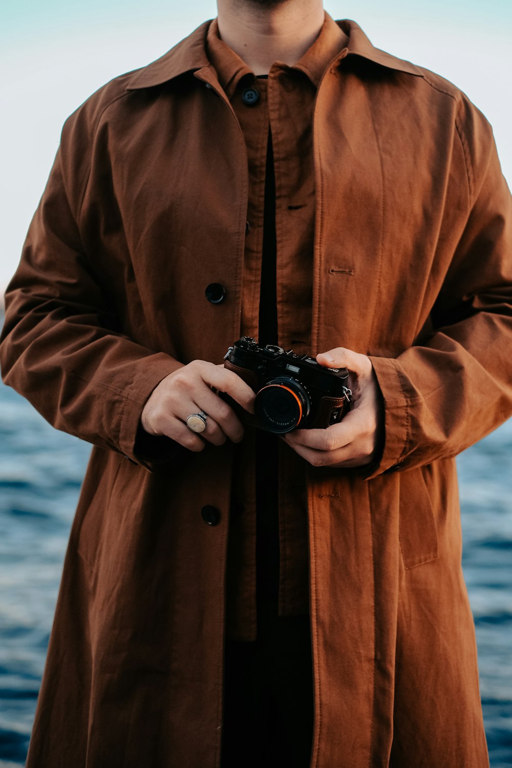 a man standing in front of a body of water holding a camera