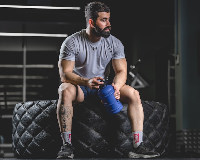 a man sitting on top of a tire holding a water bottle