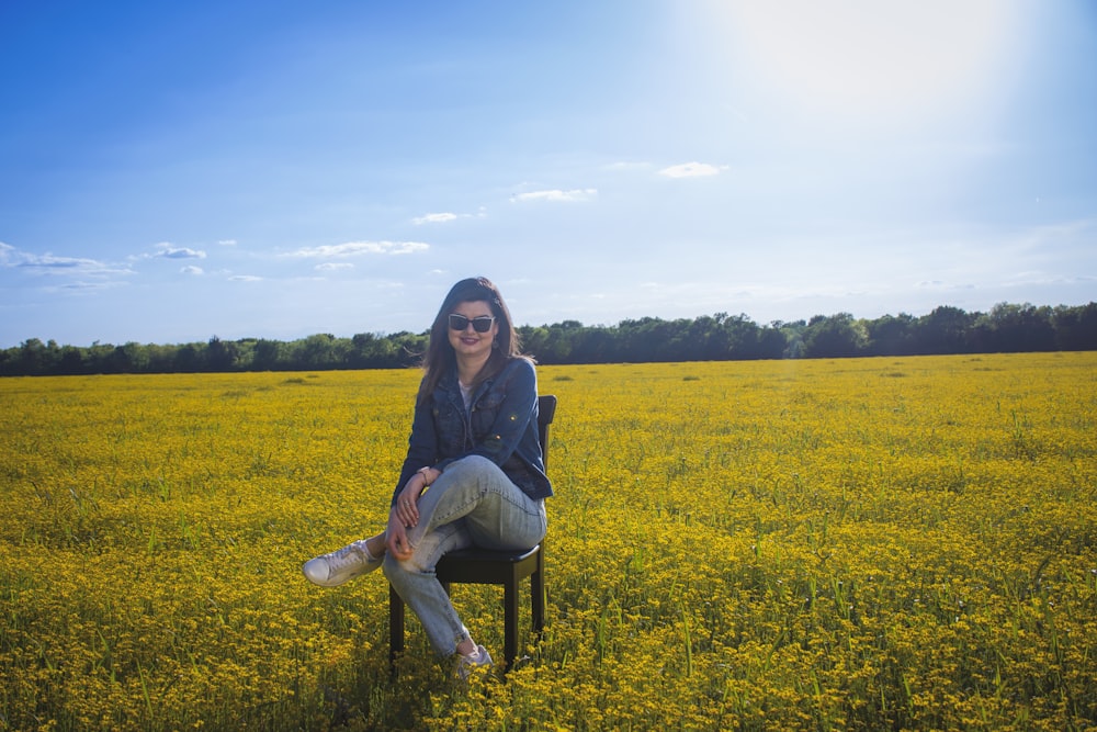 a woman sitting on a chair in a field of yellow flowers