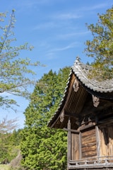 Elegant wooden pendopo structure with intricate carvings under a clear blue sky.