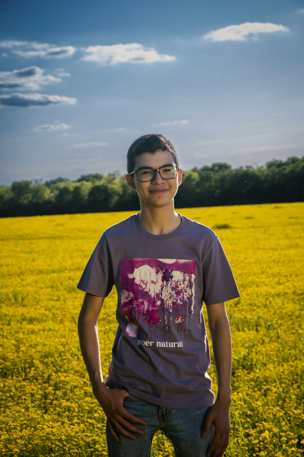 a young man standing in a field of yellow flowers