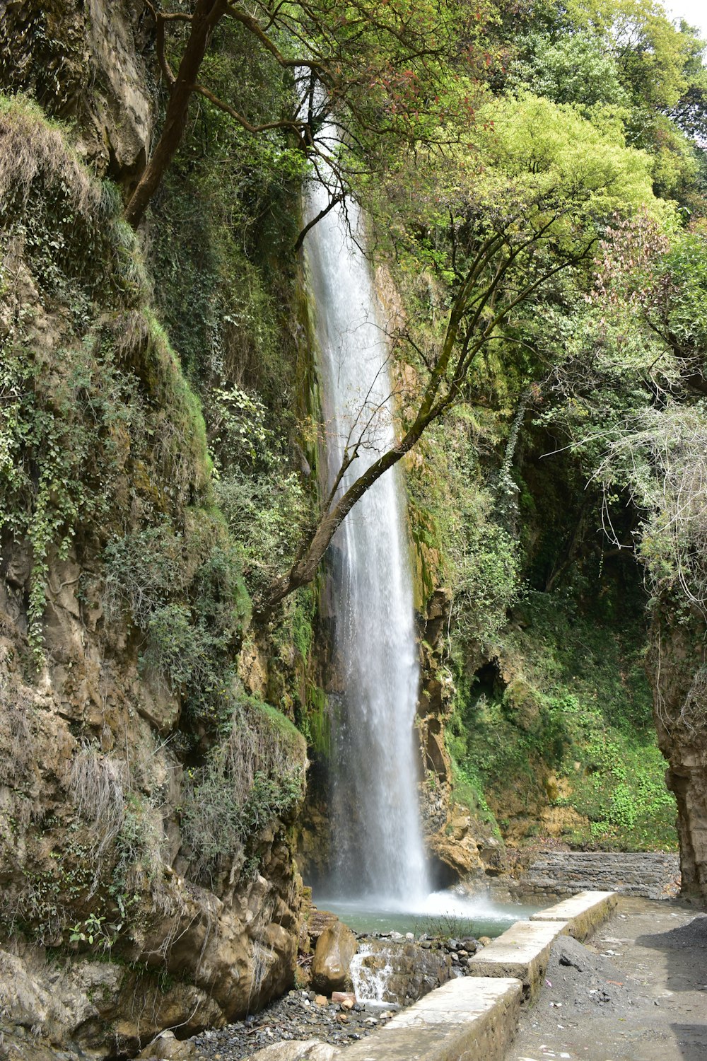 a waterfall with a man standing next to it