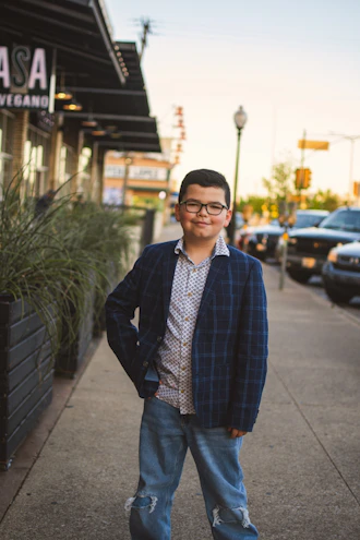 A young boy smiling confidently in a stylish casual outfit from the boys collection.