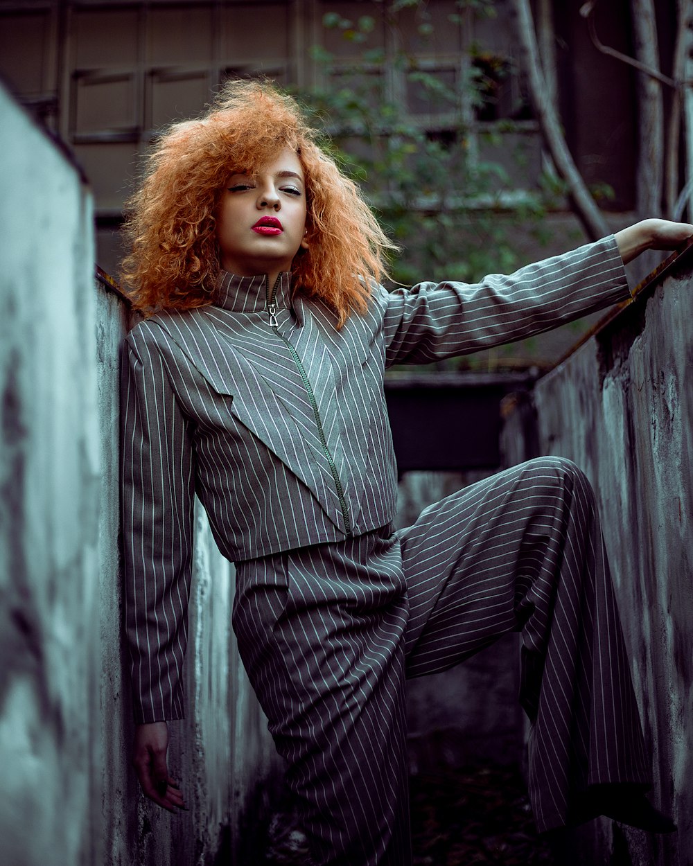 a woman with red hair leaning against a wall