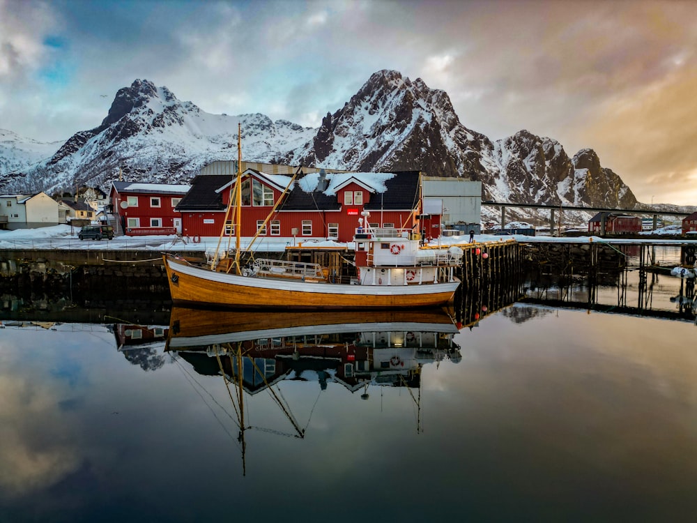 a boat sits in the water in front of a snowy mountain