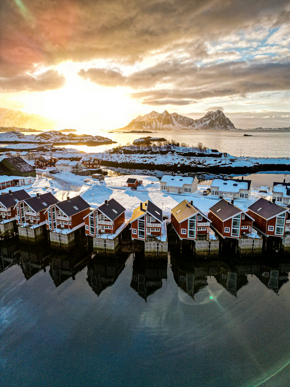 Traditional red fishing cabins of the Lofoten Islands reflected in calm water at dusk