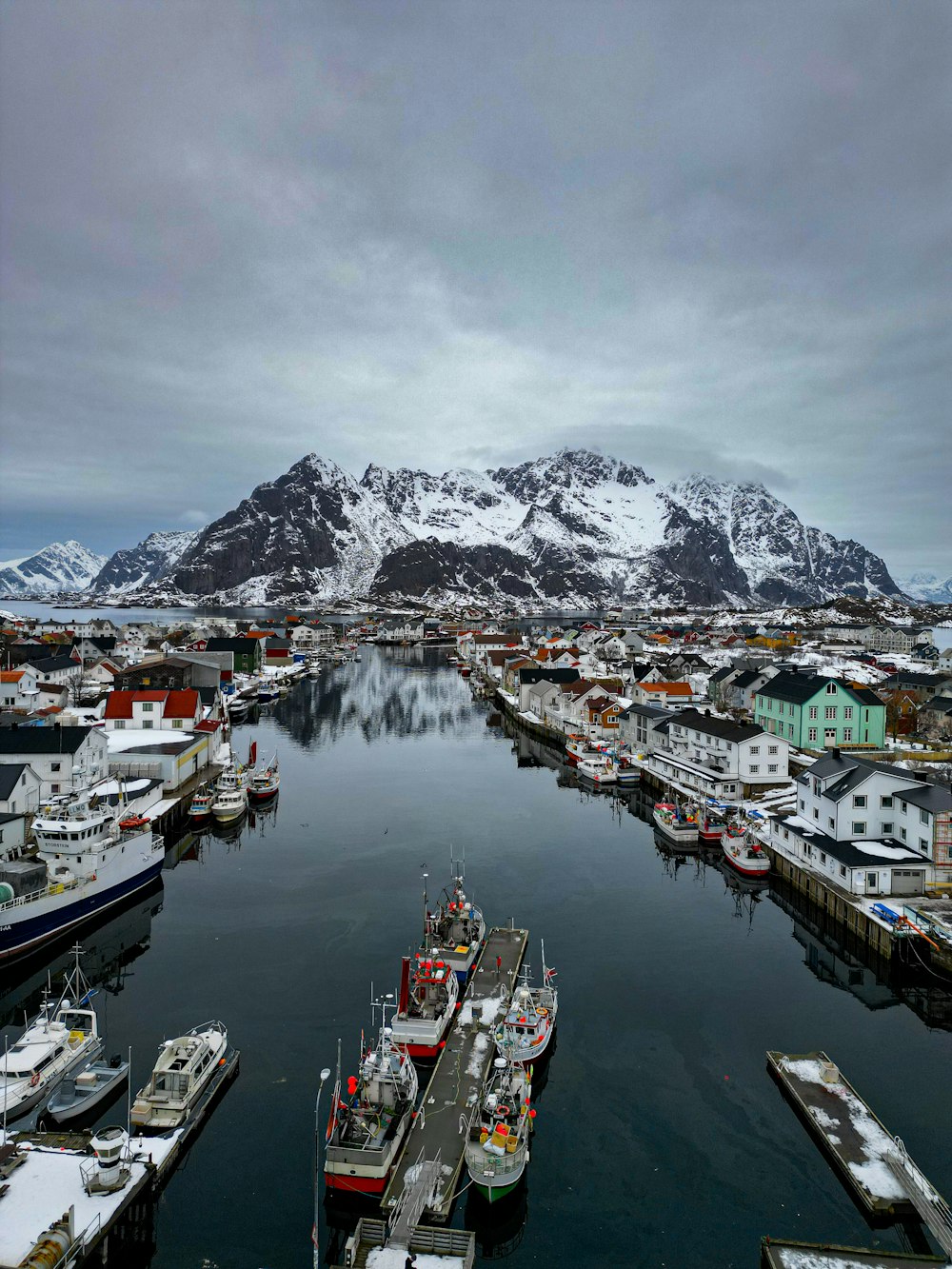 a harbor filled with lots of boats under a snow covered mountain