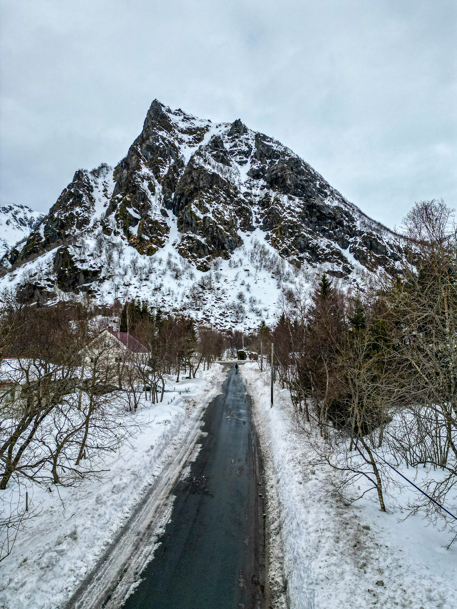 A snow-lined road approaches a mountain in Lofoten
