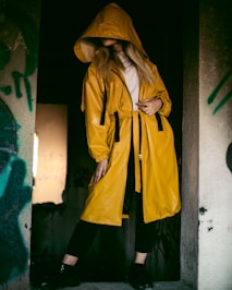 a woman in a yellow raincoat standing in a doorway