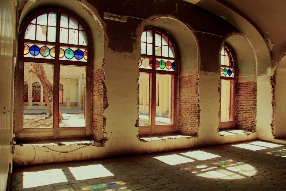 a room with three windows and a brick floor