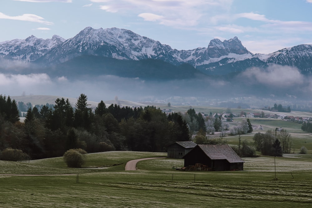 a barn in a field with mountains in the background