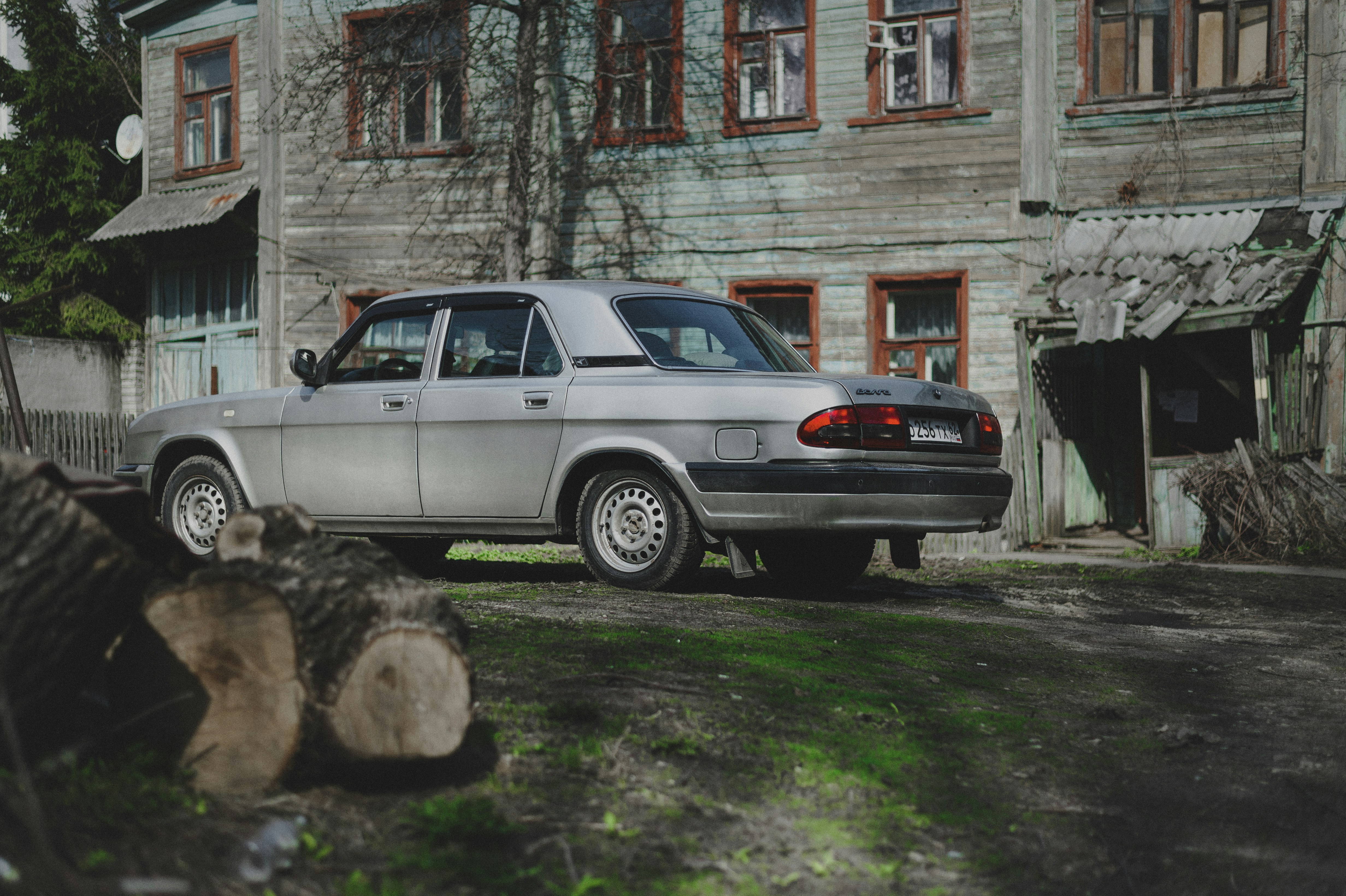 Car Volga, parked in the yard of an old wooden house.