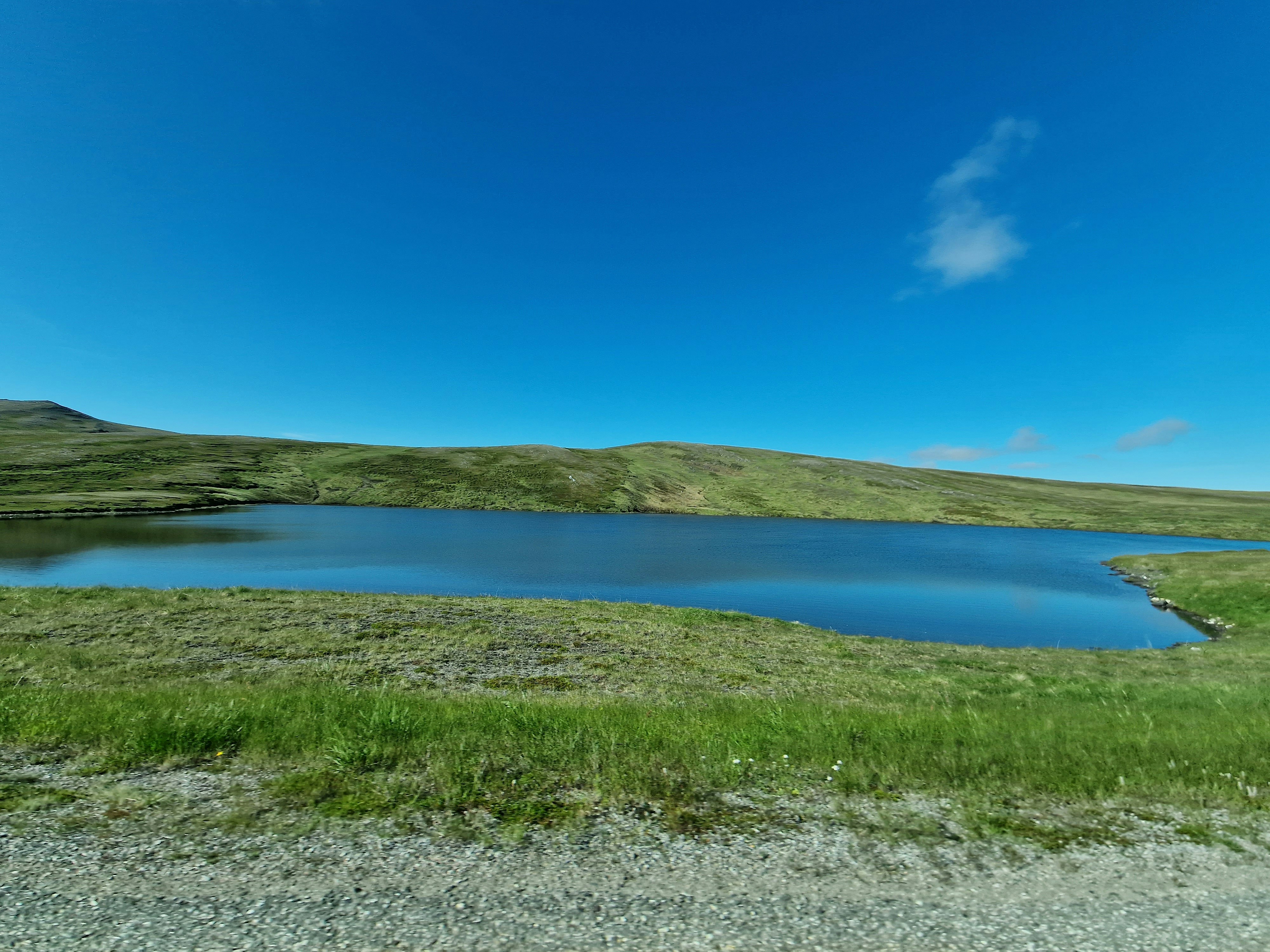 Ein großes Gewässer, umgeben von einem üppigen grünen Hügel