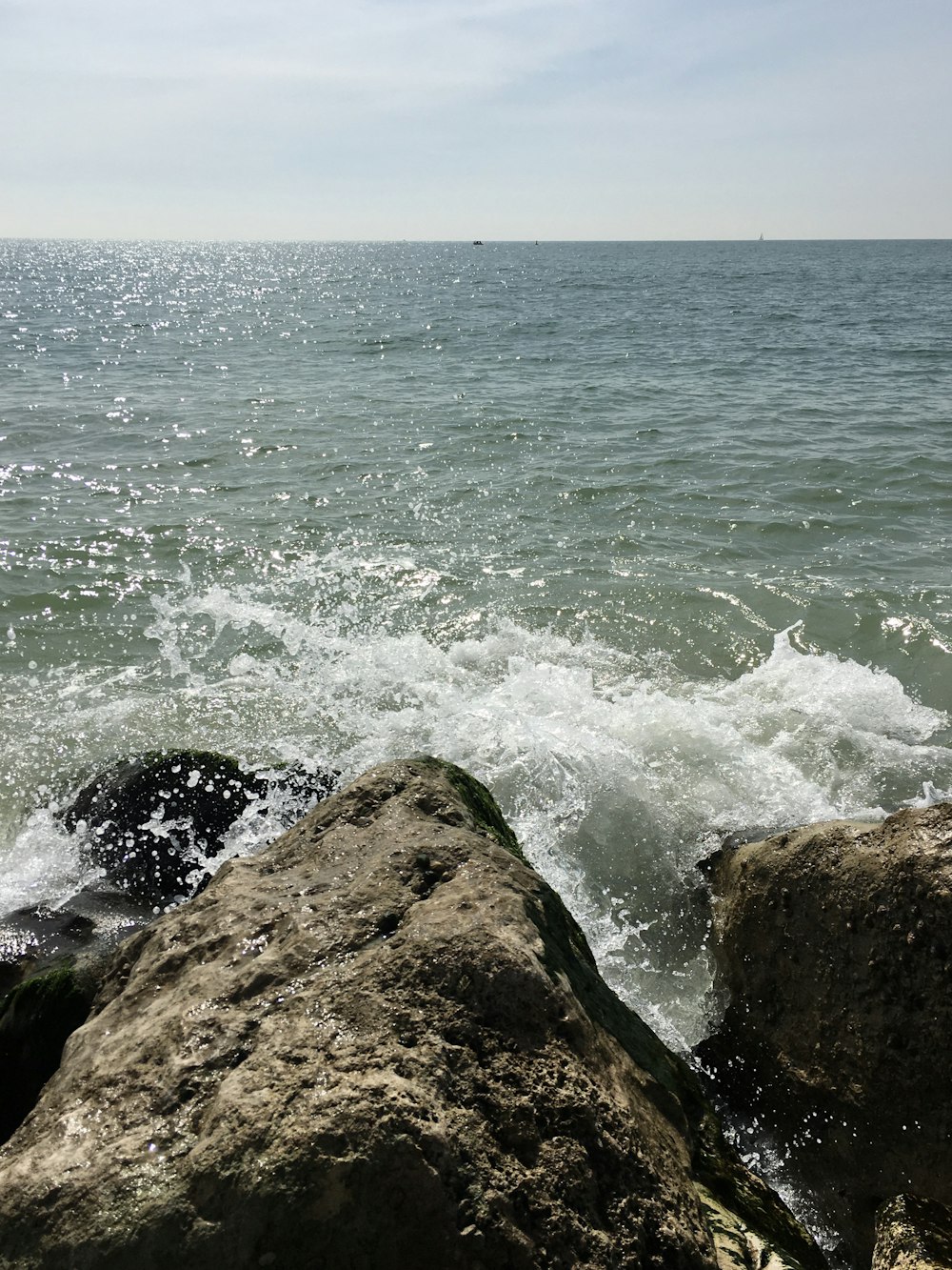 a large rock sitting on top of a beach next to the ocean