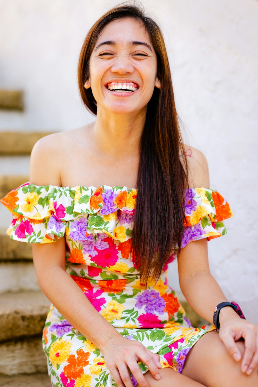 a smiling woman in a colorful dress sitting on steps