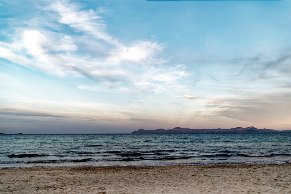 a view of a beach with a few clouds in the sky