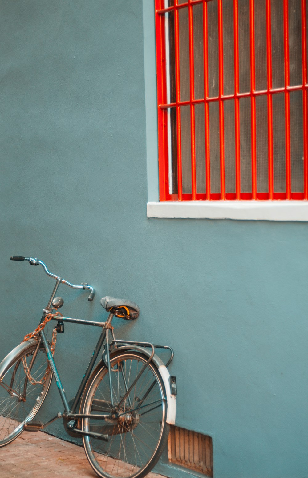 a bike leaning against a wall with a red window behind it