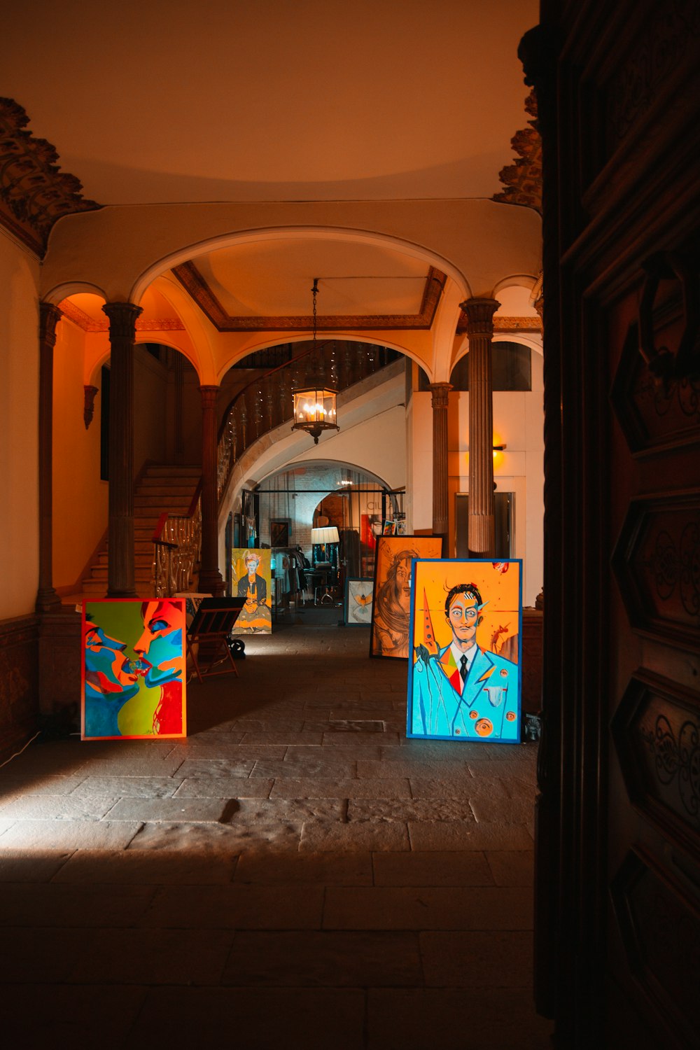a hallway with paintings on the walls and a chandelier