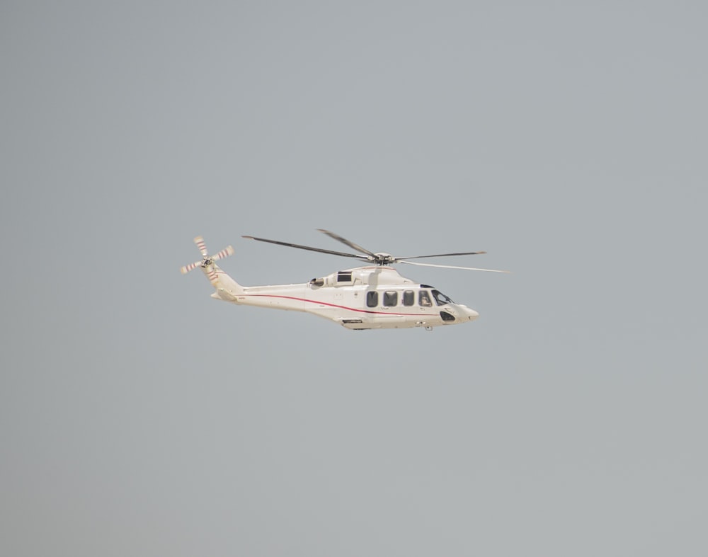 a helicopter flying in the air with a sky background