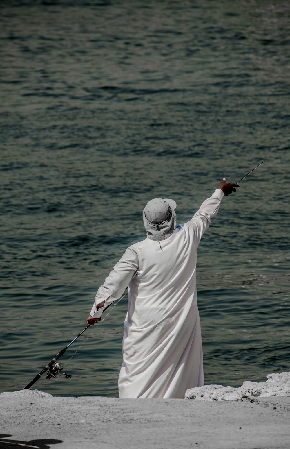 A man in a white robe holding a fishing rod photo – Free Dubai