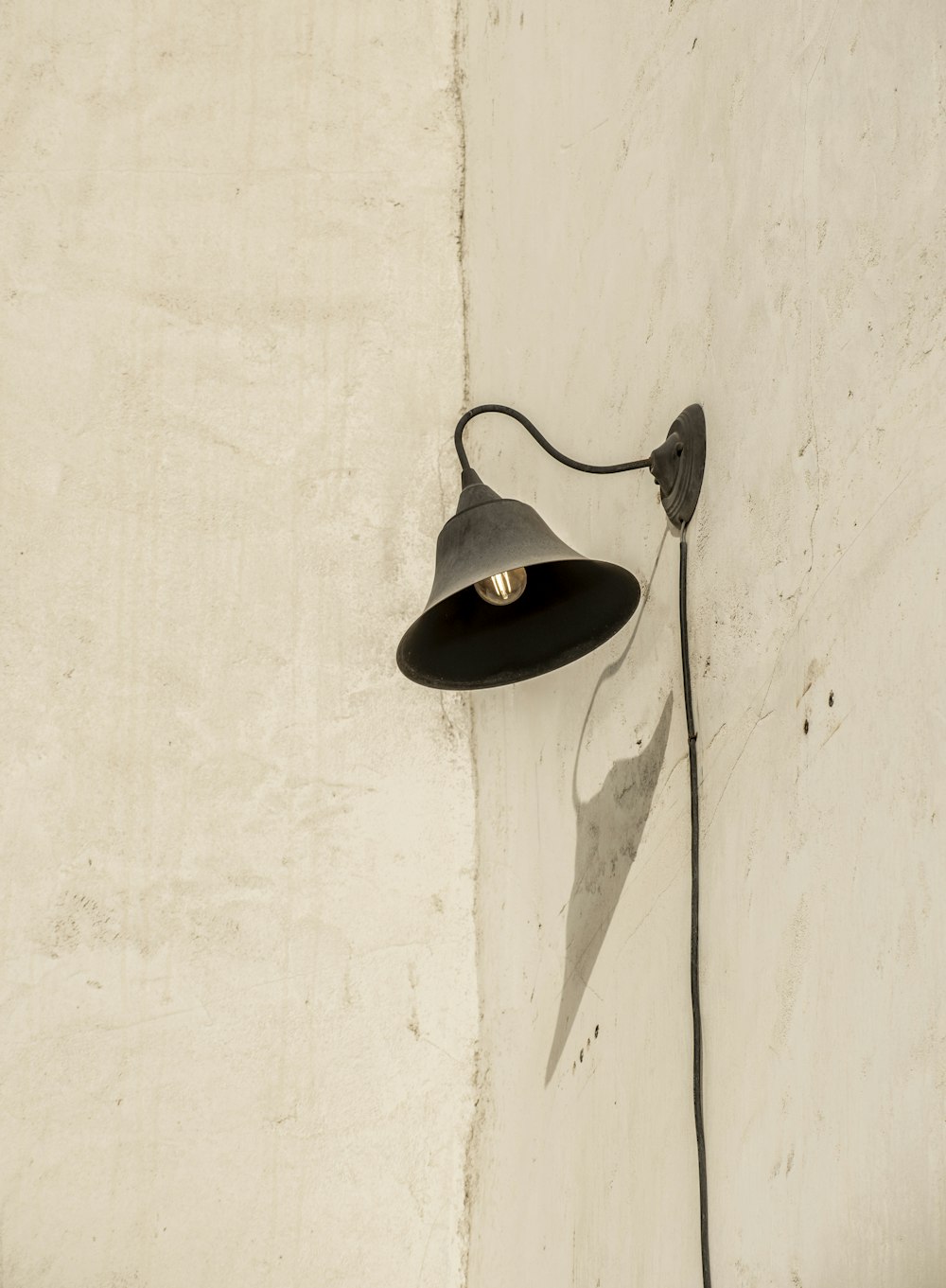 a black lamp on a white wall next to a white wall