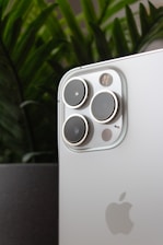 a close up of a cell phone with a plant in the background