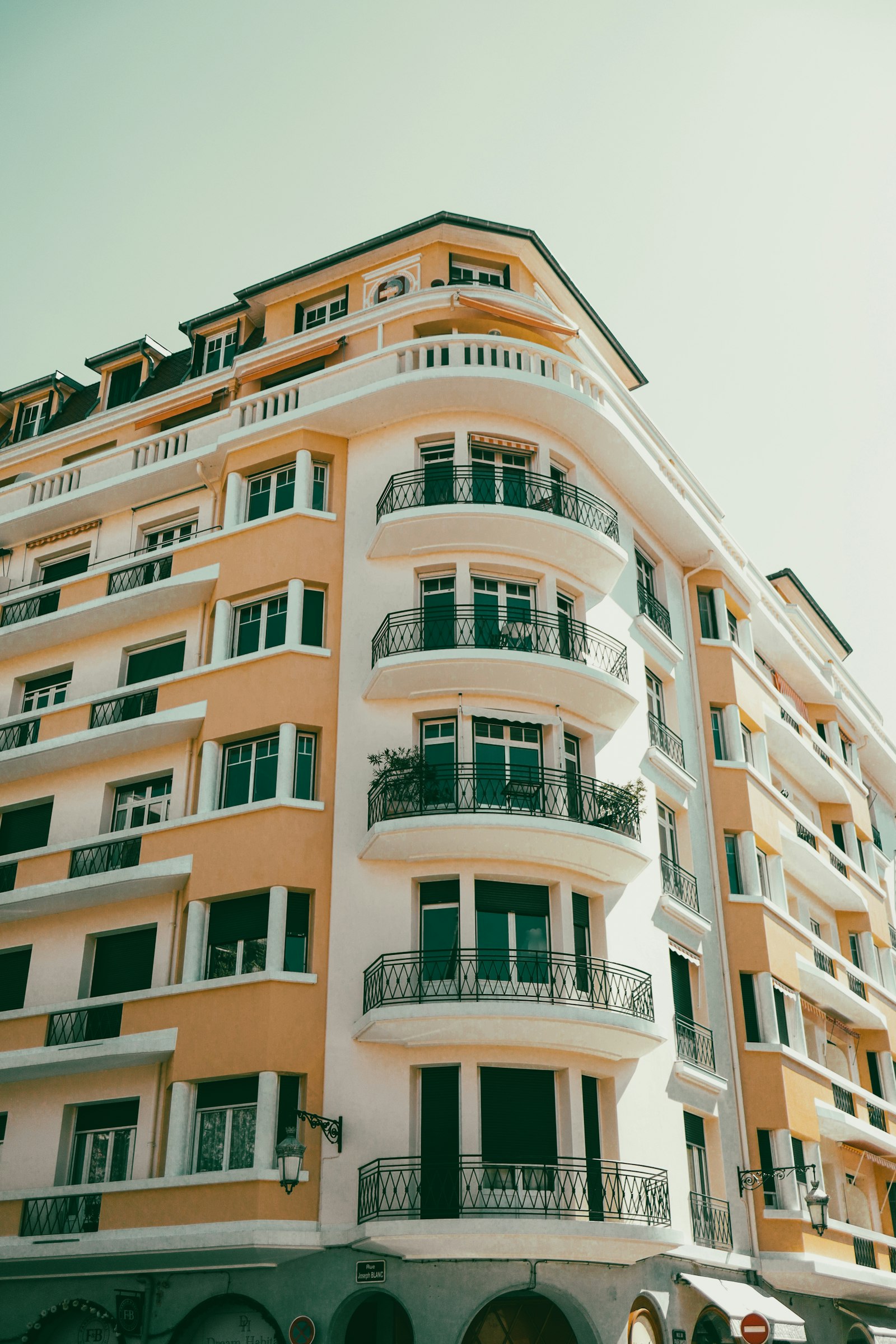 Un immeuble ancien aux balcons arrondis et aux persiennes vertes