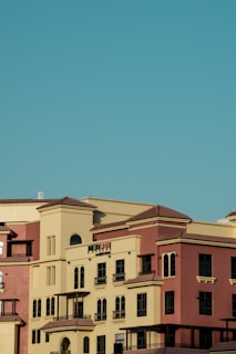 Several multi-story buildings with Mediterranean-style architecture, featuring beige and terracotta exteriors under a clear blue sky.