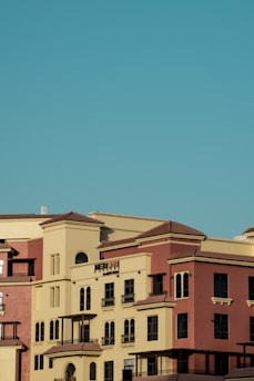 Several multi-story buildings with Mediterranean-style architecture, featuring beige and terracotta exteriors under a clear blue sky.