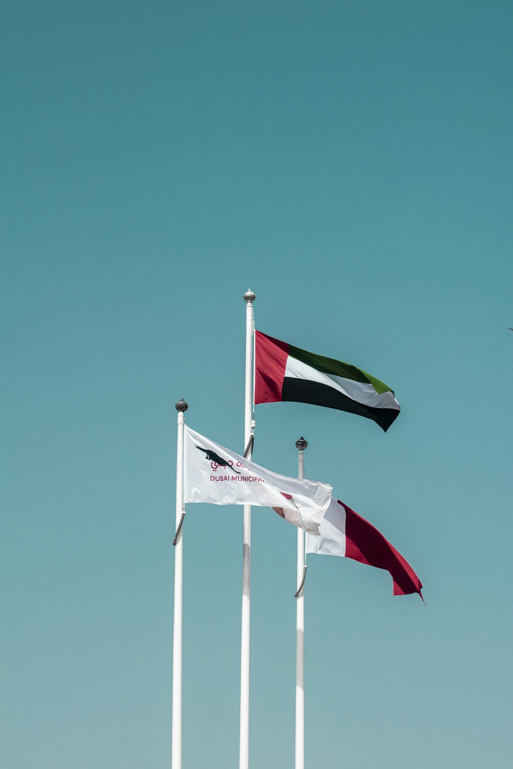 a group of three flags flying in the sky