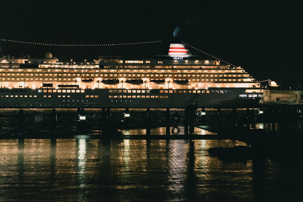a large cruise ship docked at a pier at night