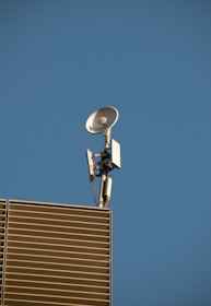 TV antenna and satellite dish installed on a rooftop against a clear blue sky.