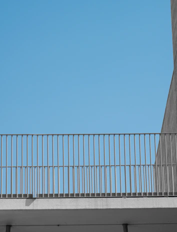 Aluminum and glass balcony railing under a bright blue sky.