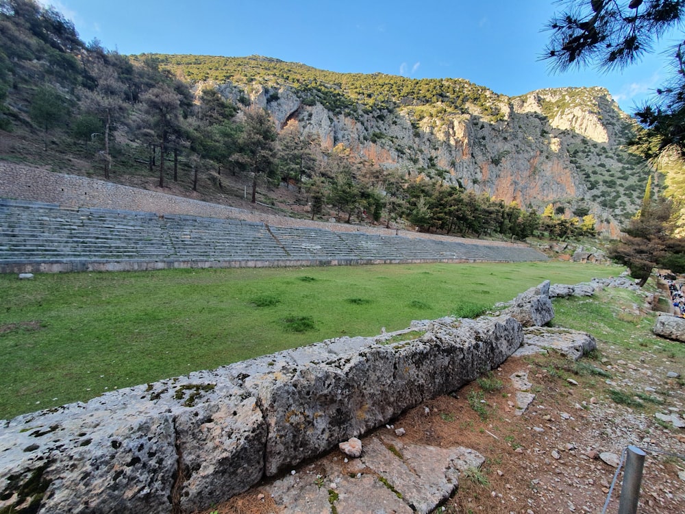 a large stone wall next to a lush green field