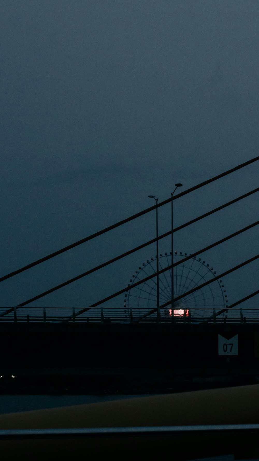 uma vista de uma ponte à noite com uma torre do relógio à distância