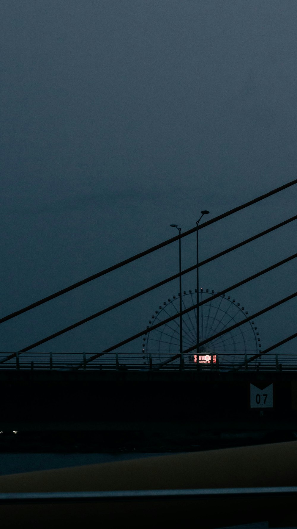 a view of a bridge at night with a clock tower in the distance