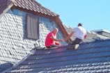 two men working on the roof of a house