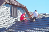 two men working on the roof of a house