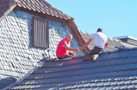 two men working on the roof of a house