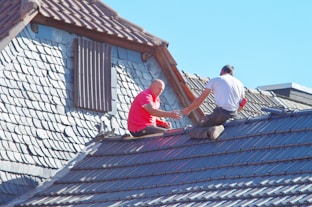 two men working on the roof of a house