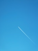 A clear blue sky with a commercial airplane flying overhead.