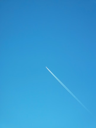 A clear blue sky with a commercial airplane flying overhead.