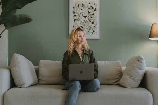 a woman sitting on a couch looking up from a laptop