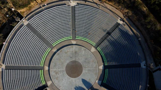 Aerial view of an urban ruin with scattered audience seating for a performance.