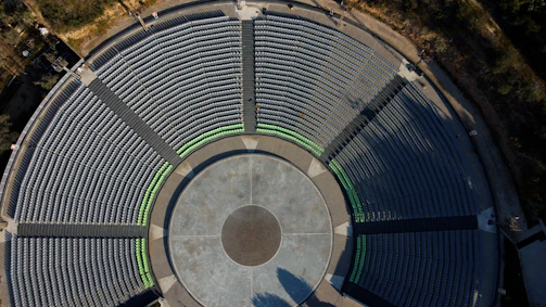Aerial view of an urban ruin with scattered audience seating for a performance.